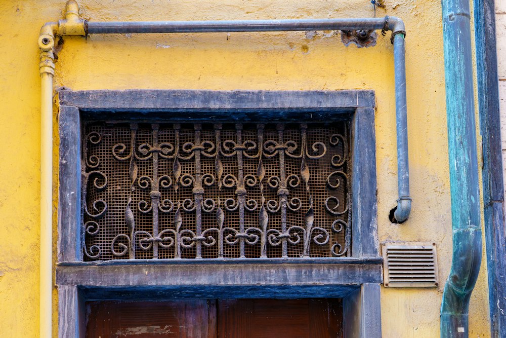 Protección ornamental de fierro en una ventana de fachada amarilla